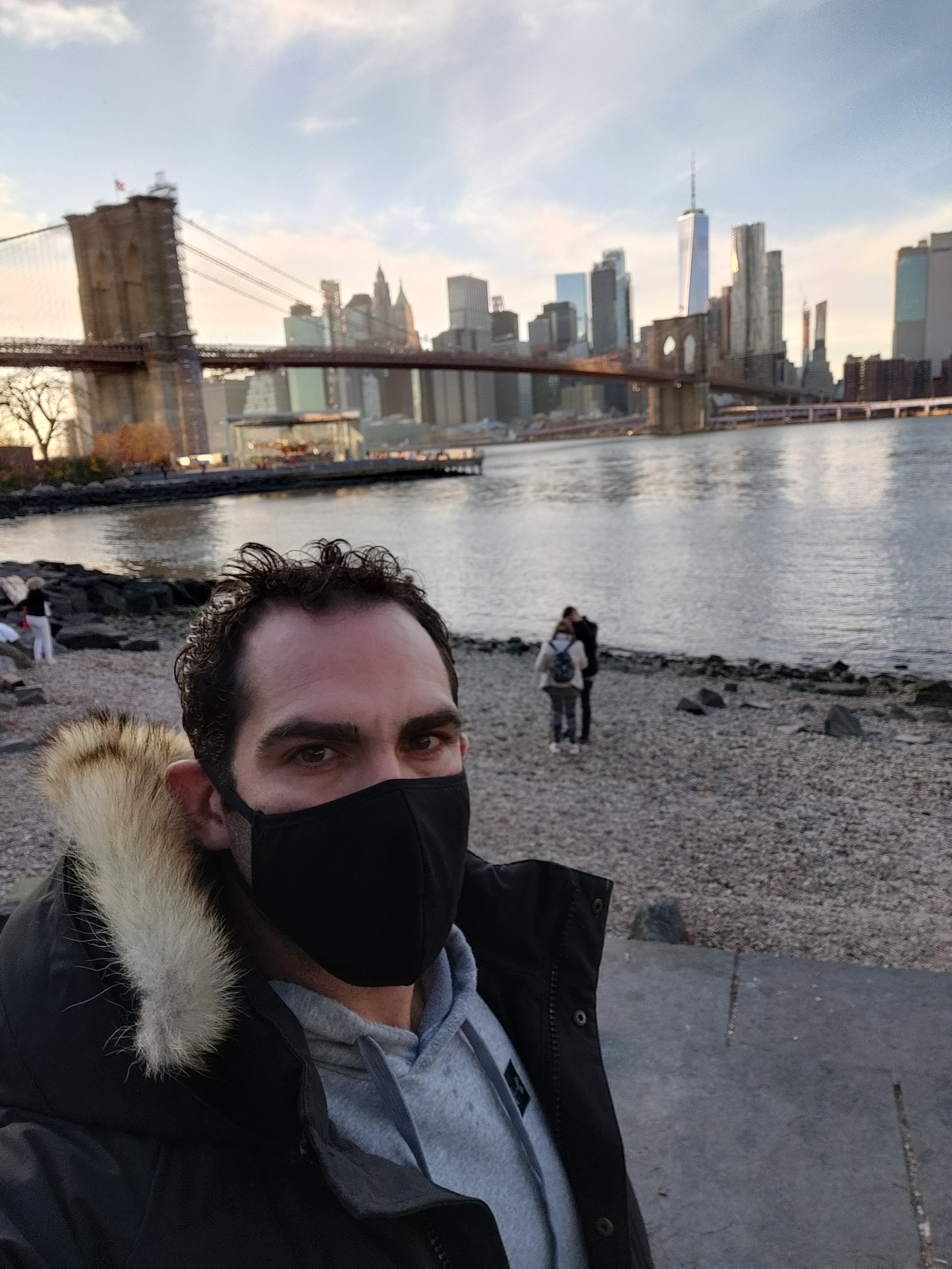 Israel Joffe in a face mask on the Brooklyn waterfront with the Manhattan skyline behind him